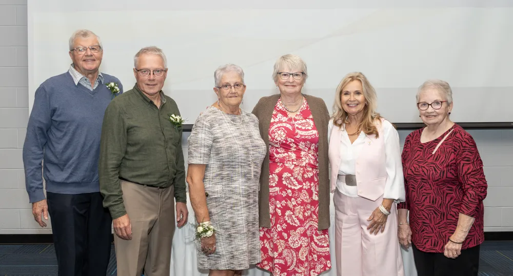 image of six people standing shoulder to shoulder in front of a projector screen