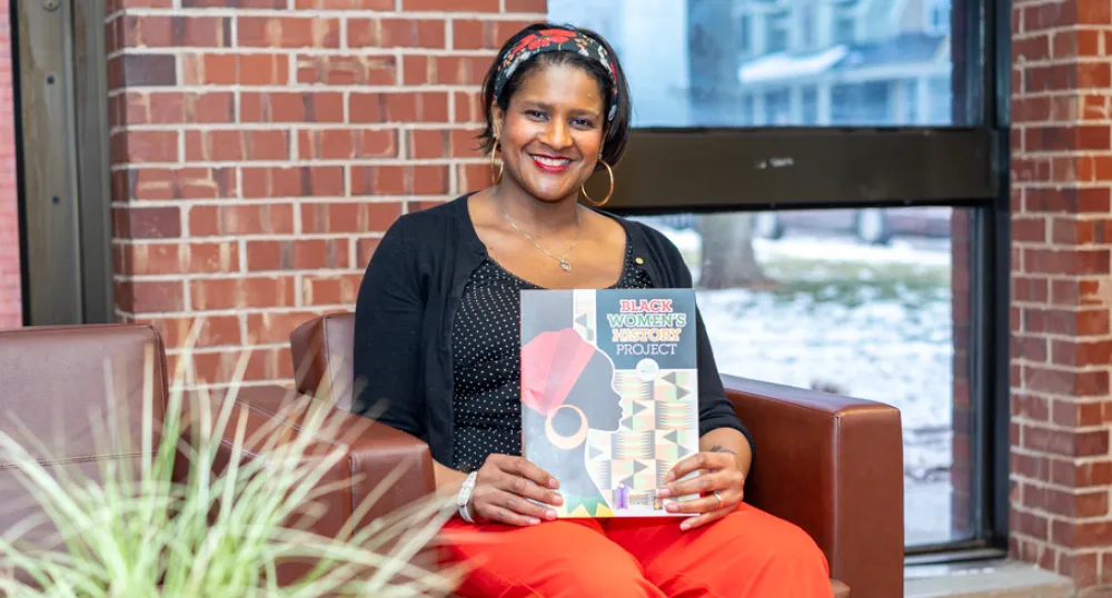 image of a woman sitting on a chair holding a booklet on her lap
