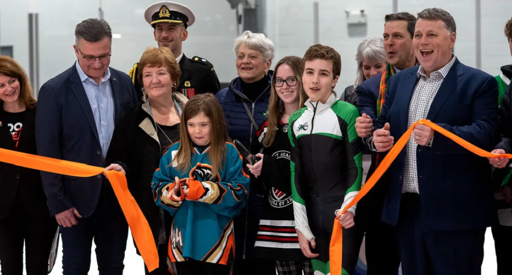 image of a group of people standing in a rink holding a ribbon during an opening ceremony