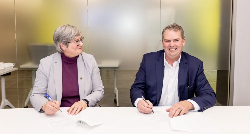 Dr. Heather Bruce and Minister Thompson sit next to each other at a table