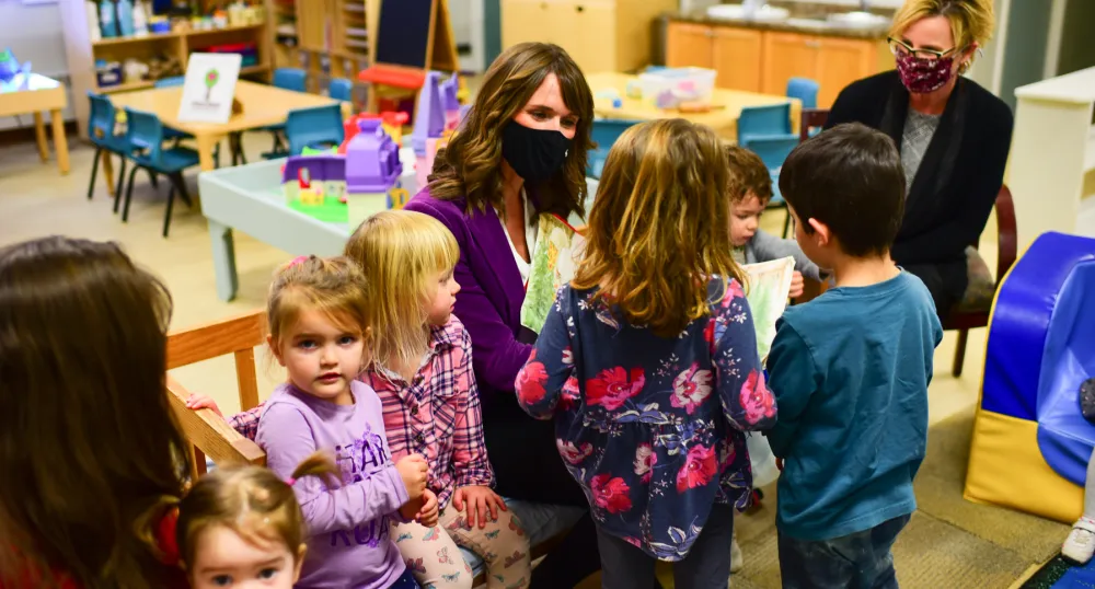 image of some adults and children sitting in a classroom reading area