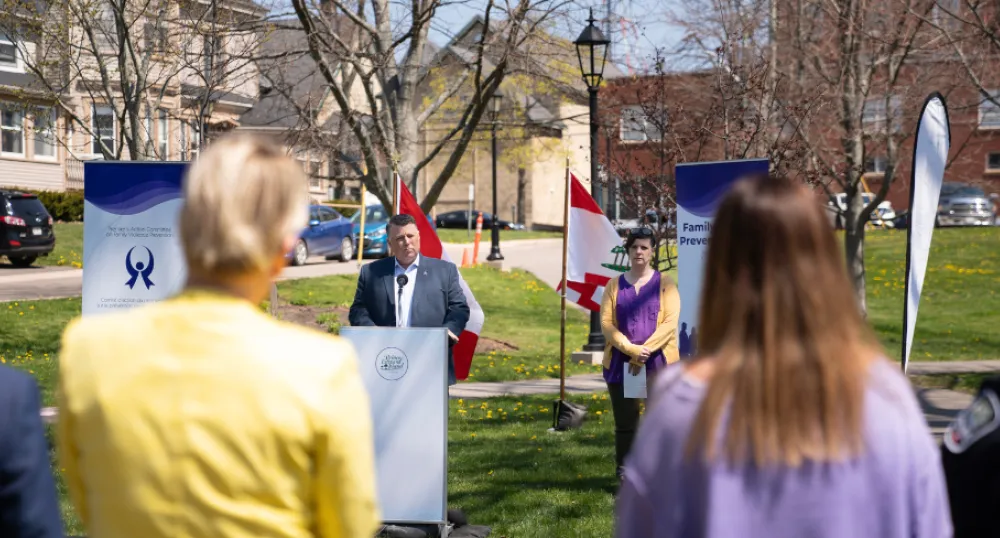 image of people in a park listening to a person behind a podium speaks