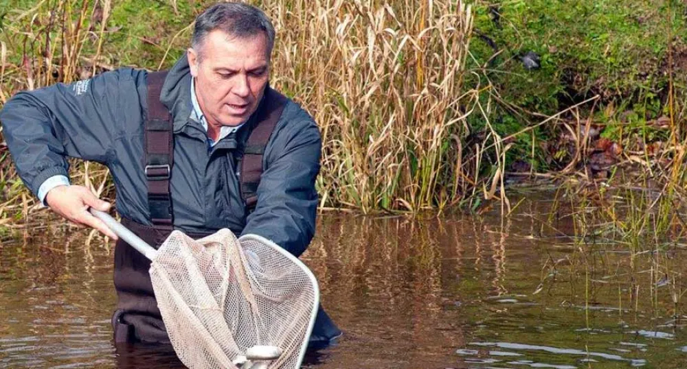 Minister Mitchell releasing fish into a river