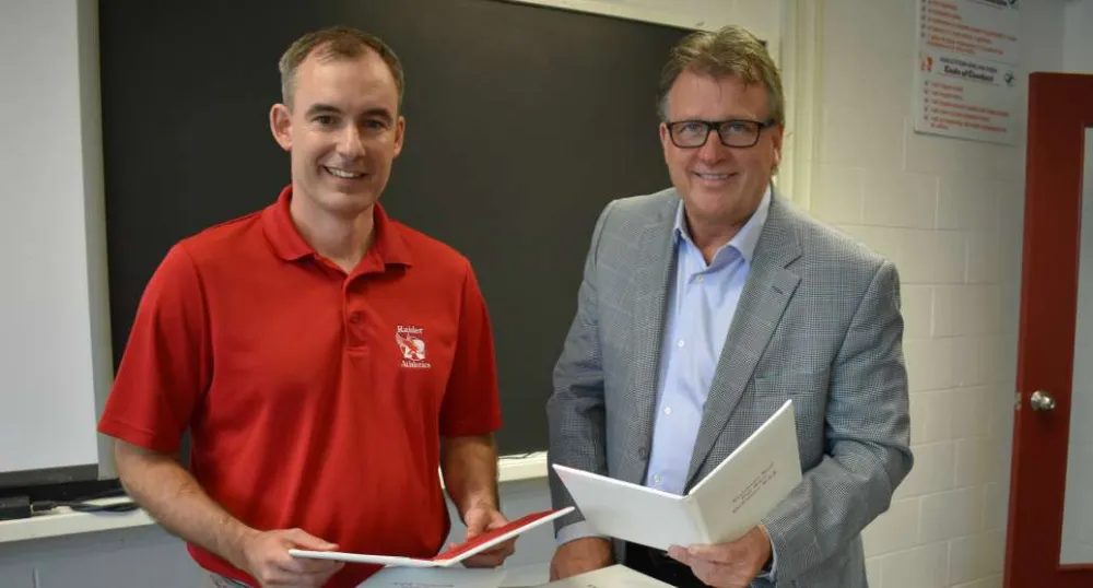 Two people holding signed high school diplomas