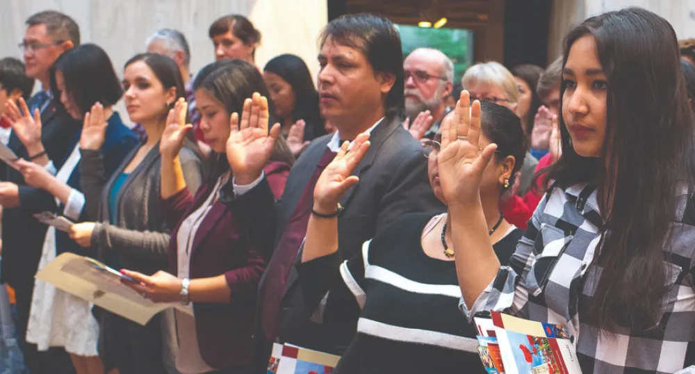 image of a group of people standing shoulder to shoulder with one arm - palm out - held at shoulder height