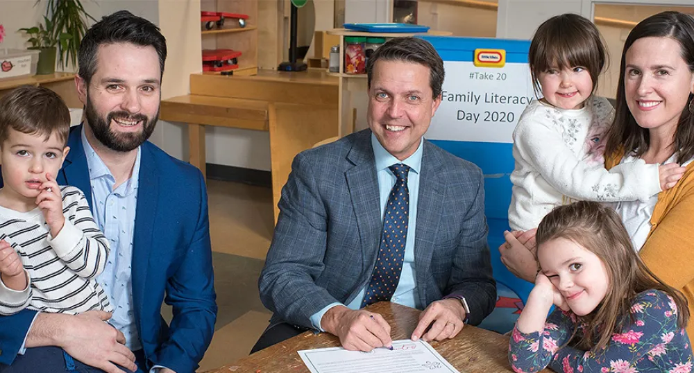 People sitting at a table holding young children in their arms.