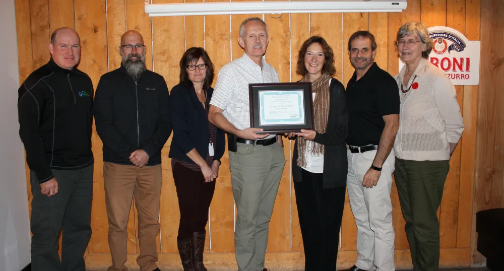 Photo shows Alex Forbes in the centre holding the award certificate flanked by six subcommittee members.