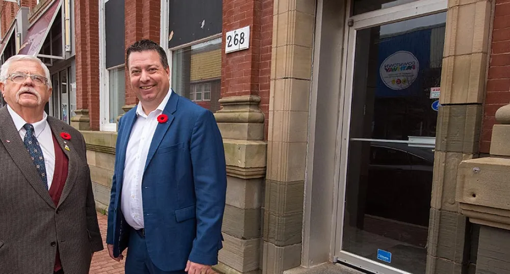 Two people standing in front of a storefront building