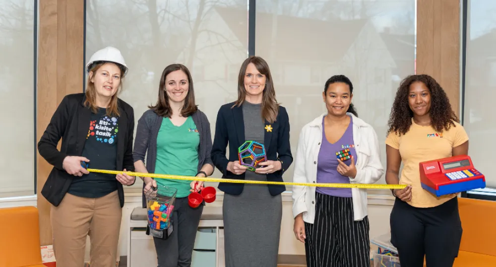 image of  five people standing shoulder to shoulder inside a building while holding some play objects