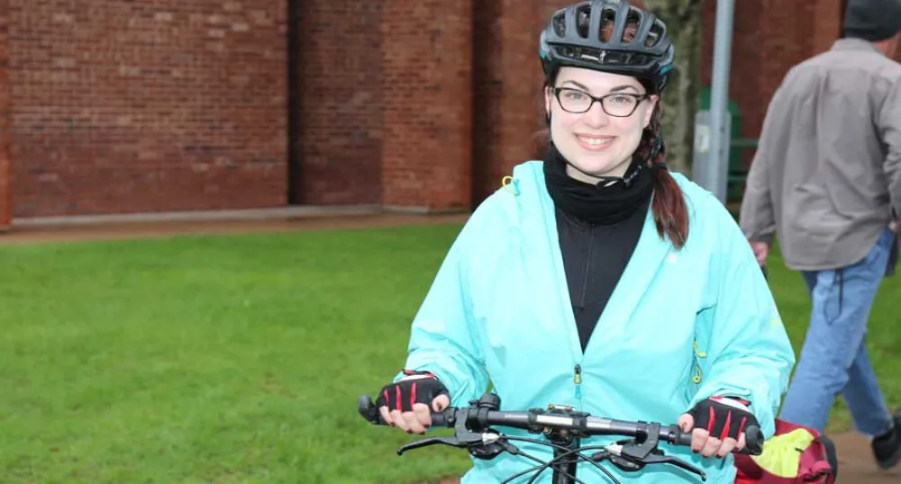 Female biker standing in front of workplace with her bike.