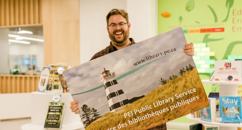 image of a person holding a large postcard with a picture of a lighthouse on it