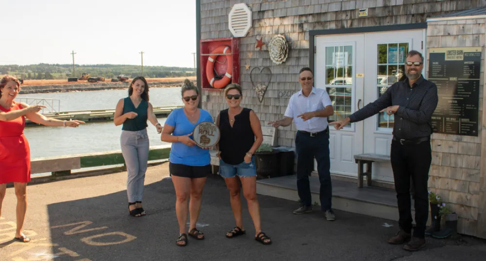 Staff from the Lobster Barn stand, along with others, outside their restaurant holding their winning plaque