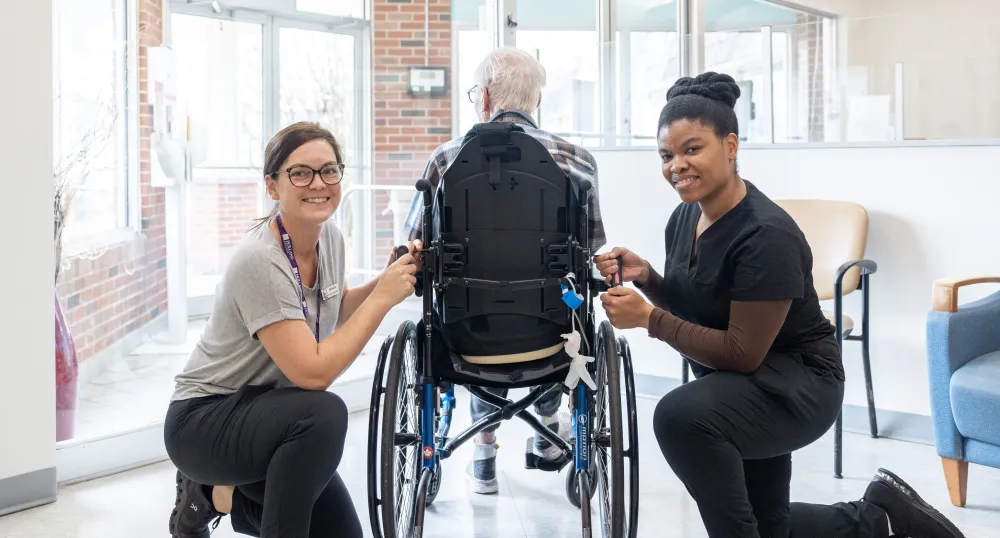 image of two people beside a person in a wheel chair inside a building foyer