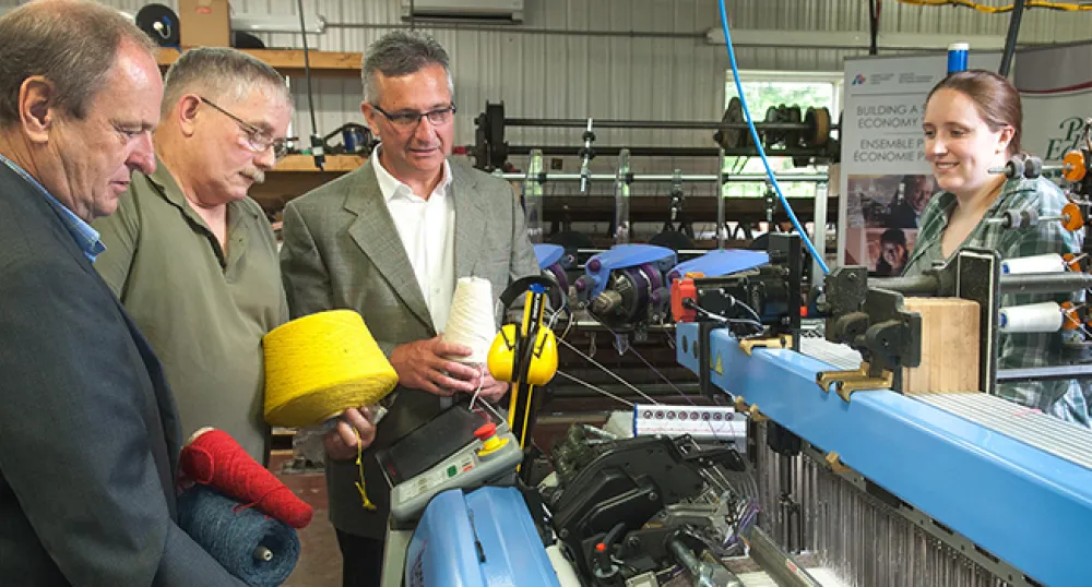 Four people looking at loom machine