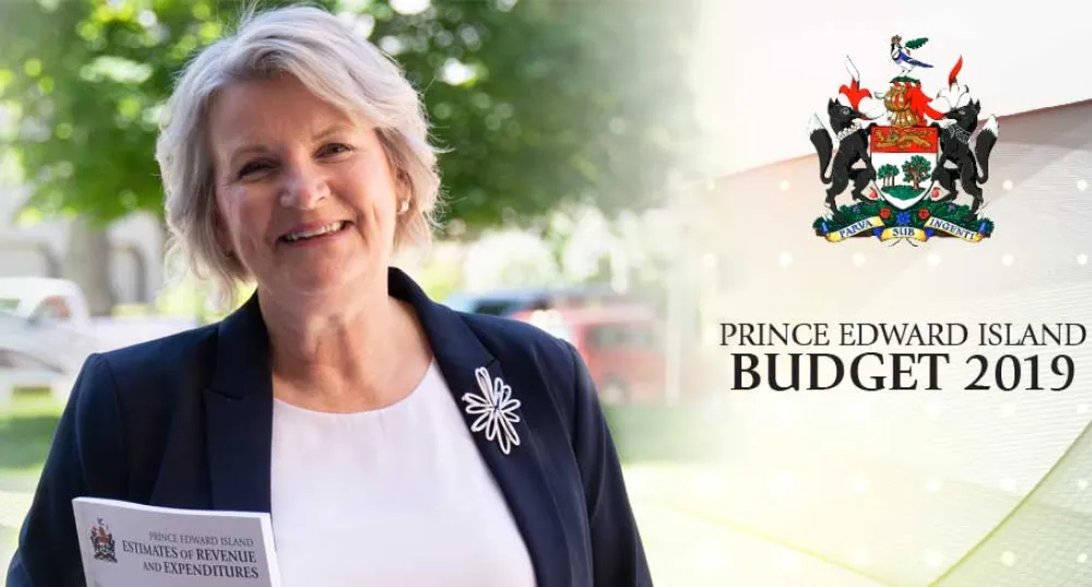 Finance Minister Darlene Compton stands holding a copy of the 2019 - 2020 operating budget