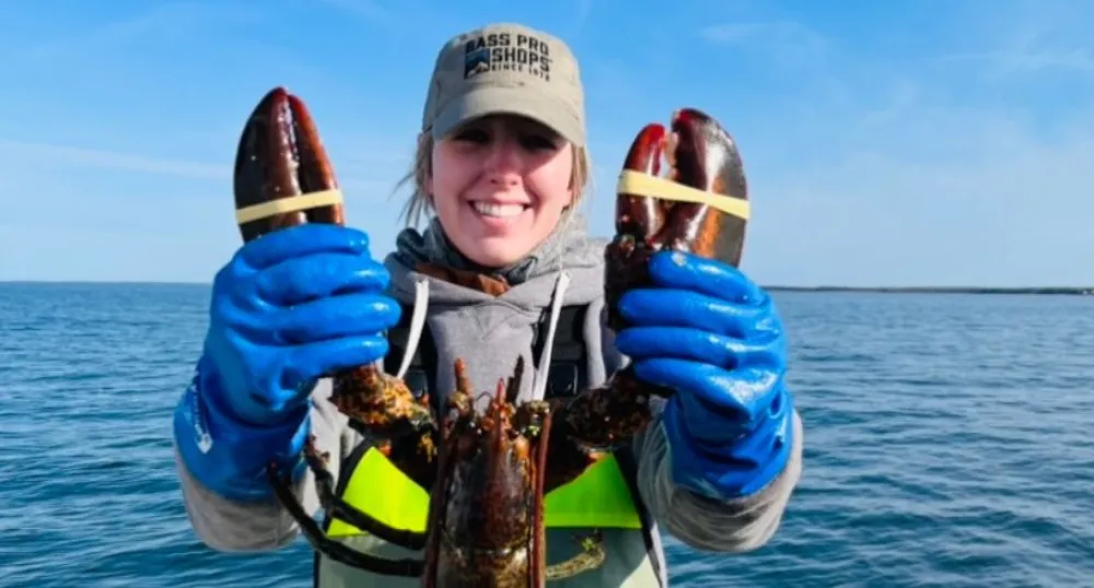 image d&#039;une personne sur un bateau de pêche tenant un homard devant elle.