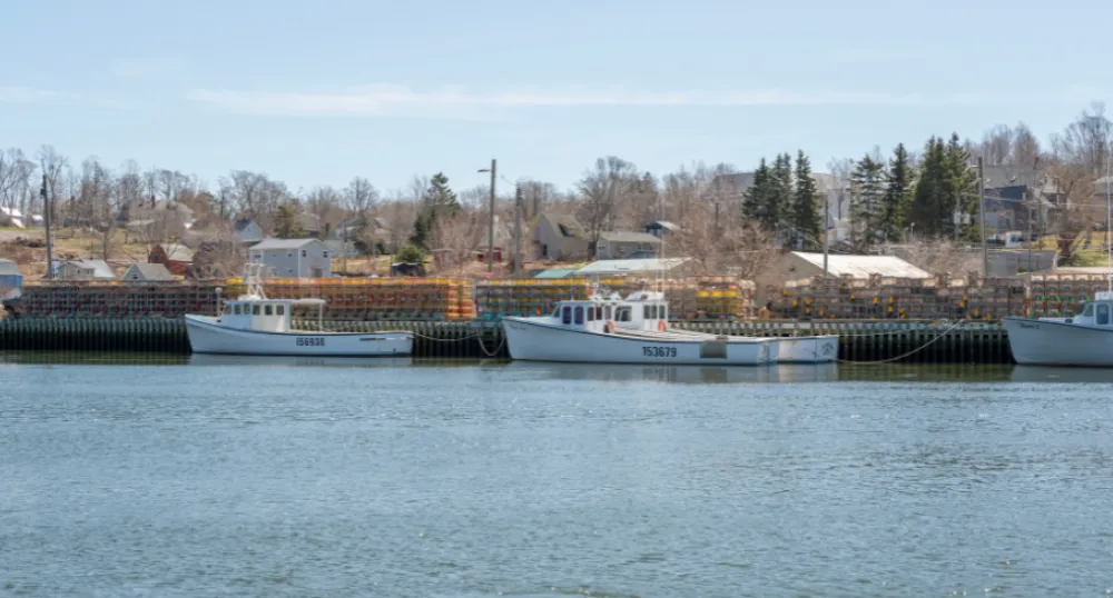 image d&#039;une pêche amarrée à un quai avec des casiers à homard sur le quai