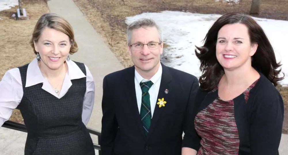 Minster Henderson and two people standing in fronot of Coles Building