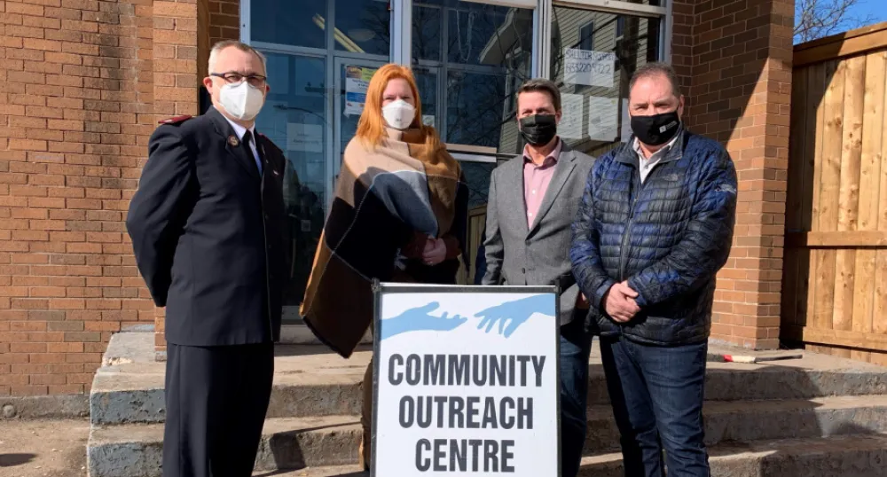 image of four people standing shulder to shoulder in front of steps of a building