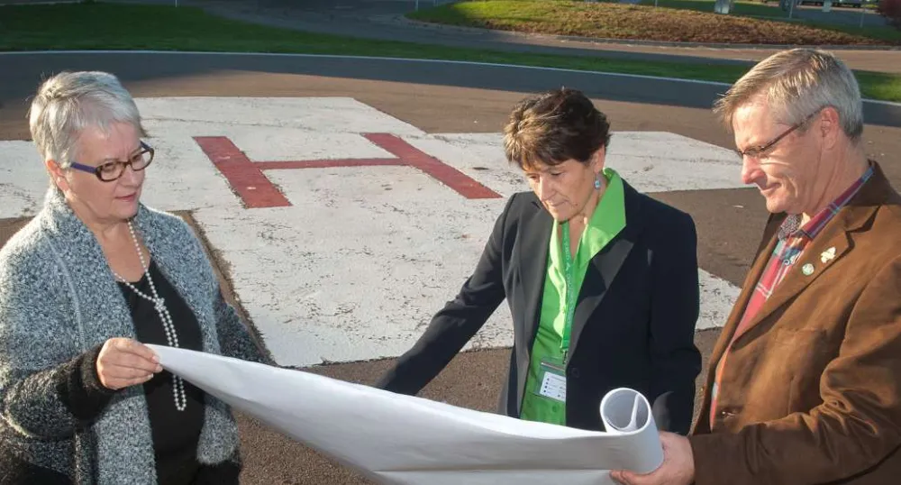 Minister Biggar and Minister henderson and one other person review construction plans near the PCH Helipad
