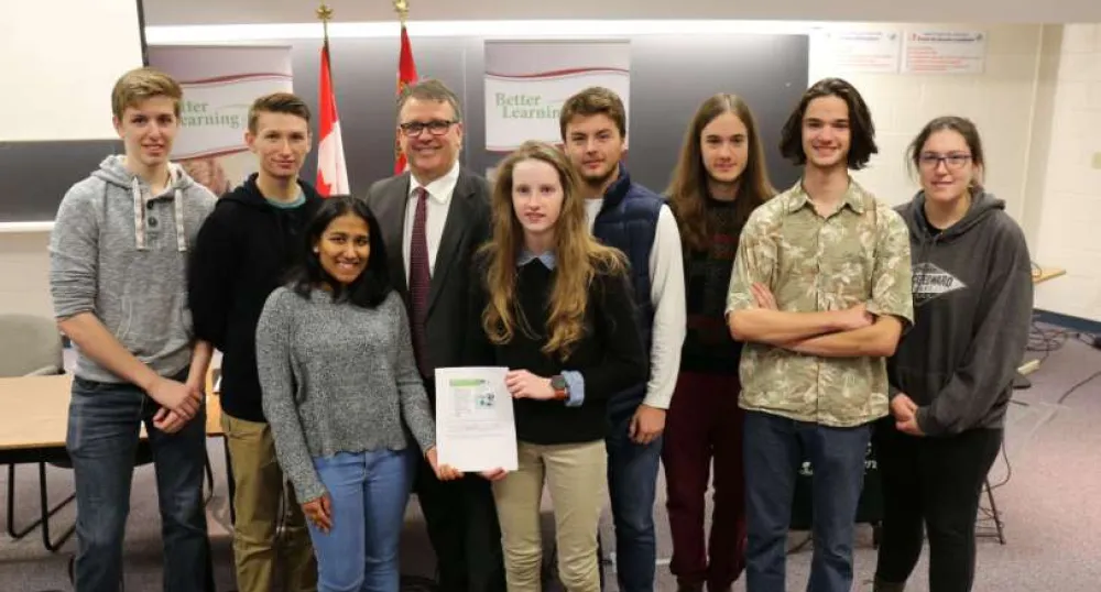 Minister Curries stands with a group of high school students