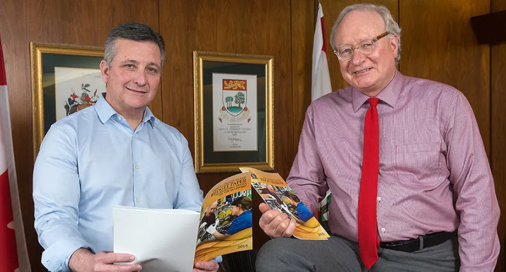 Photo shows Minister Heath MacDonald and Premier Wade MacLauchlan holding copies of the 2018-19 operating budget.
