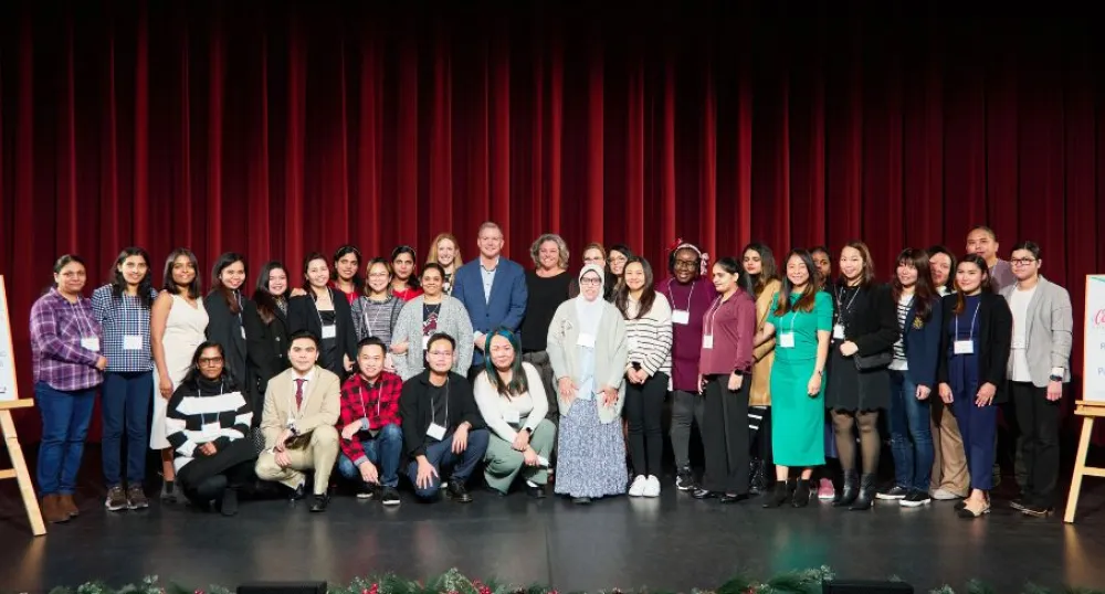image of a group of people standing shoulder to shoulder on a stage with curtains in the background