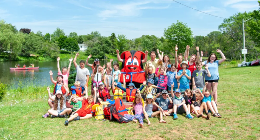 A group of Children wearing life jackets in front of a pond