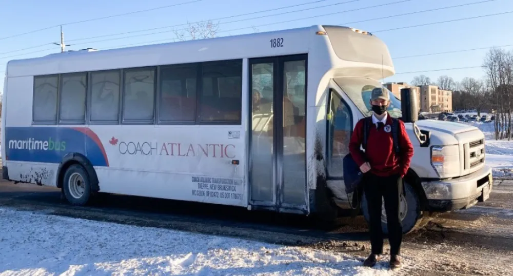 Boy standing beside public transit bus