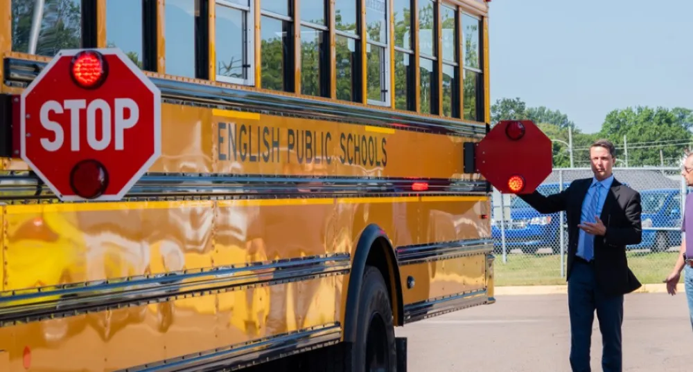 Two people standing beside a school bus