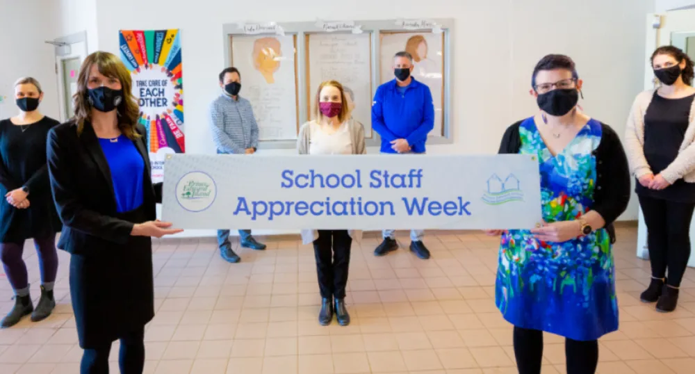 image of two people holding a sign and other people standing behind them