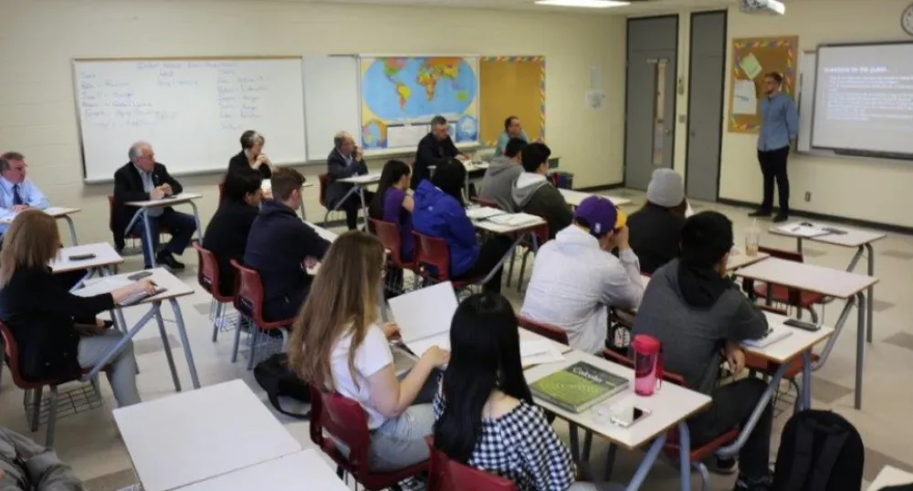 Grade 12 students Connor Crosby and Young Hao Yu stand making a presentation to their Global Issues class at Colonel Gray