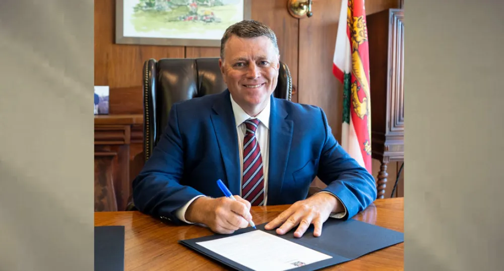 image of a man sitting at a desk signing a document