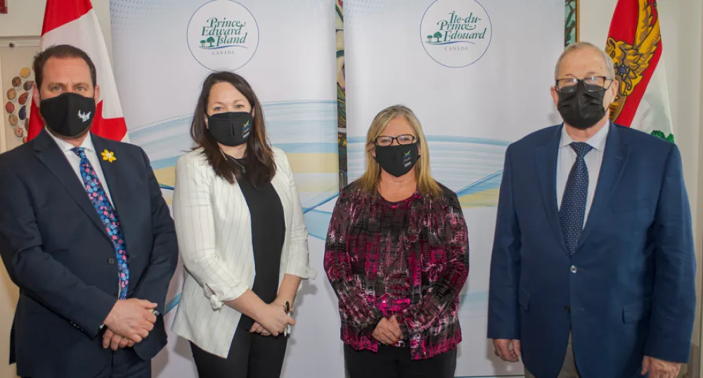 Standing in a row, wearing facemasks: PEI Minister James Aylward, Stratford Town Councilors Jill Burridge and Gail MacDonald, and Federal Minister Lawrence MacAulay