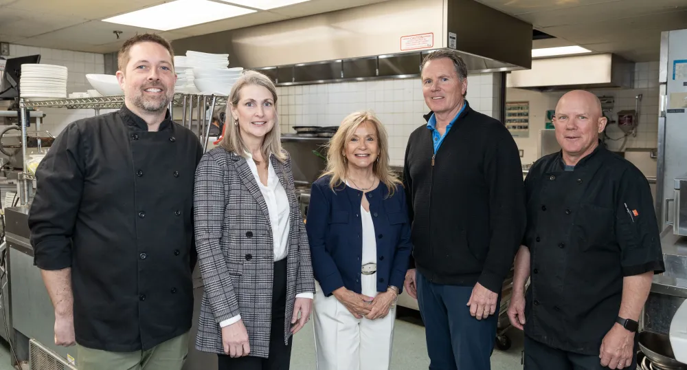 Five people stand next to each other smiling