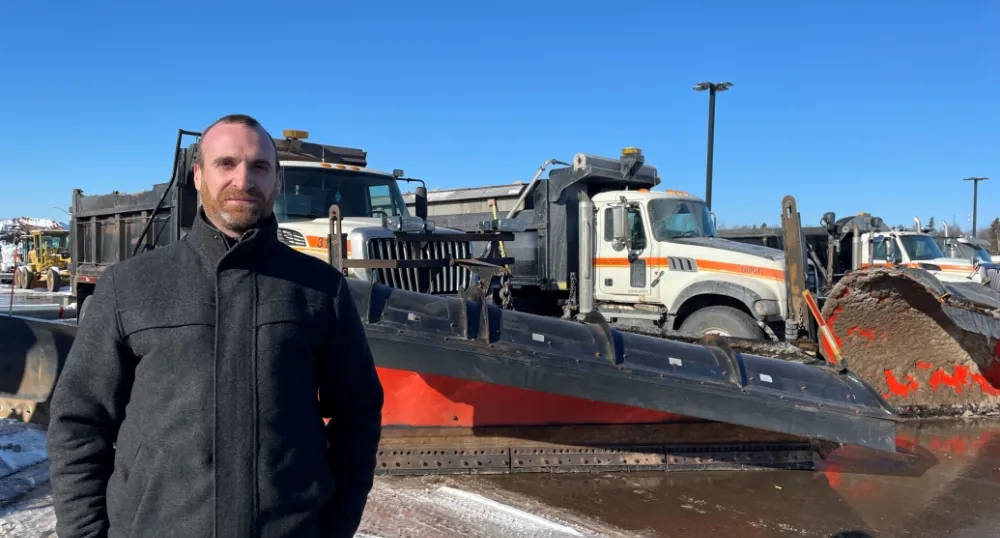 Stephen Szwarc, Director of Highway Maintenance, standing beside truck plows