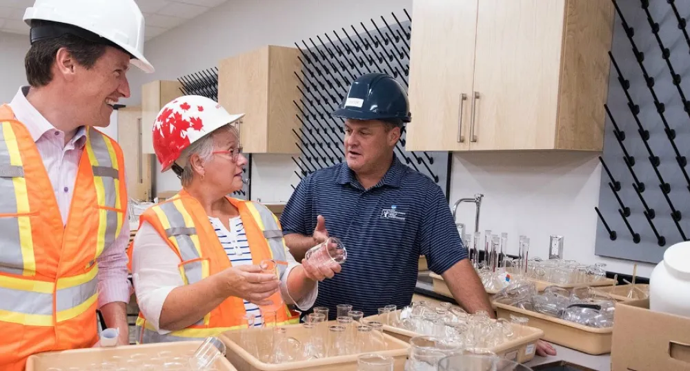 Photo shows two men and a woman examining new science and cooking supplies