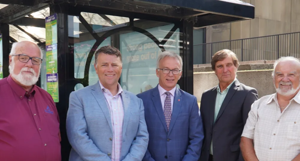 Five people standing shoulder to shoulder in front of a bus stop