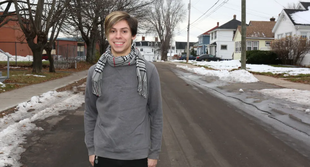 Tyler Murnaghan stands alone on a snowy city street smiling at the camera.