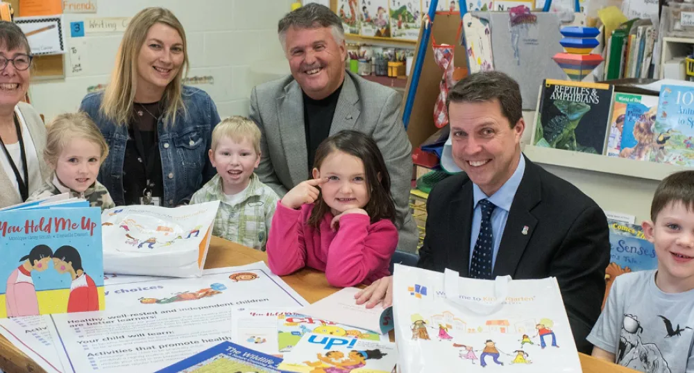 Children and adults sitting at school table with books