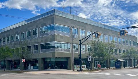 Vue extérieure d’un bâtiment. On aperçoit un passage pour piétons et un abribus