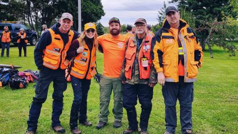 Five PEI Ground Search and Rescue members wearing bright orange vests.