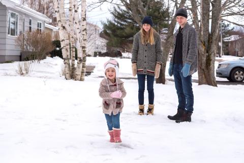 young parents and a little girl playing in the snow