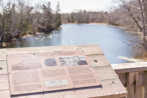 image of a small sign on a wooden bridge with a pond in the background