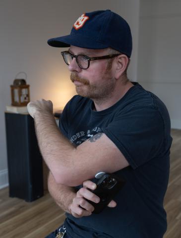 A man holds his phone near a plastic disc on his elbow