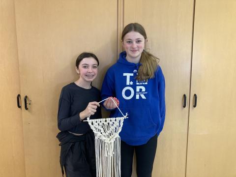 image of two young people standing in front of cupboards holding macrame