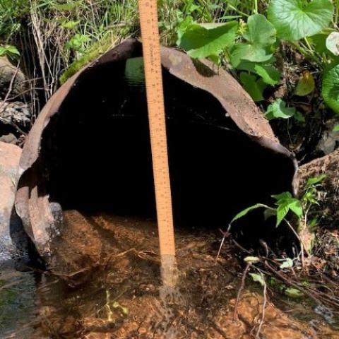 image of a rusted culvert and a measuring stick