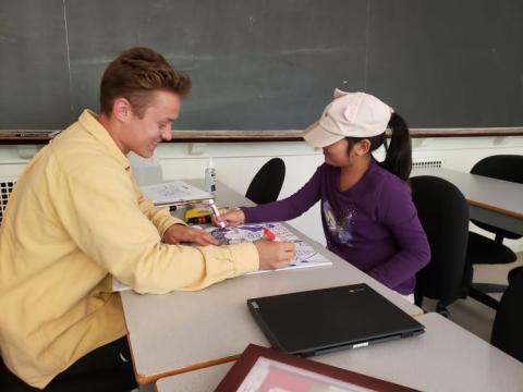 A tutor and young child sitting together at a table.