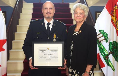 Un homme blanc et une femme blanche se tiennent côte à côte en souriant.