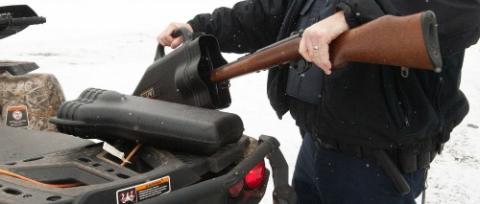 A Conservation Officer is shown placing a firearm into a case for transport. 